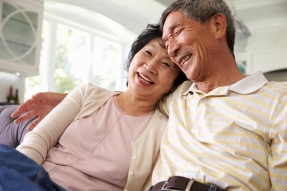 Senior Asian Couple At Home Relaxing On Sofa Together